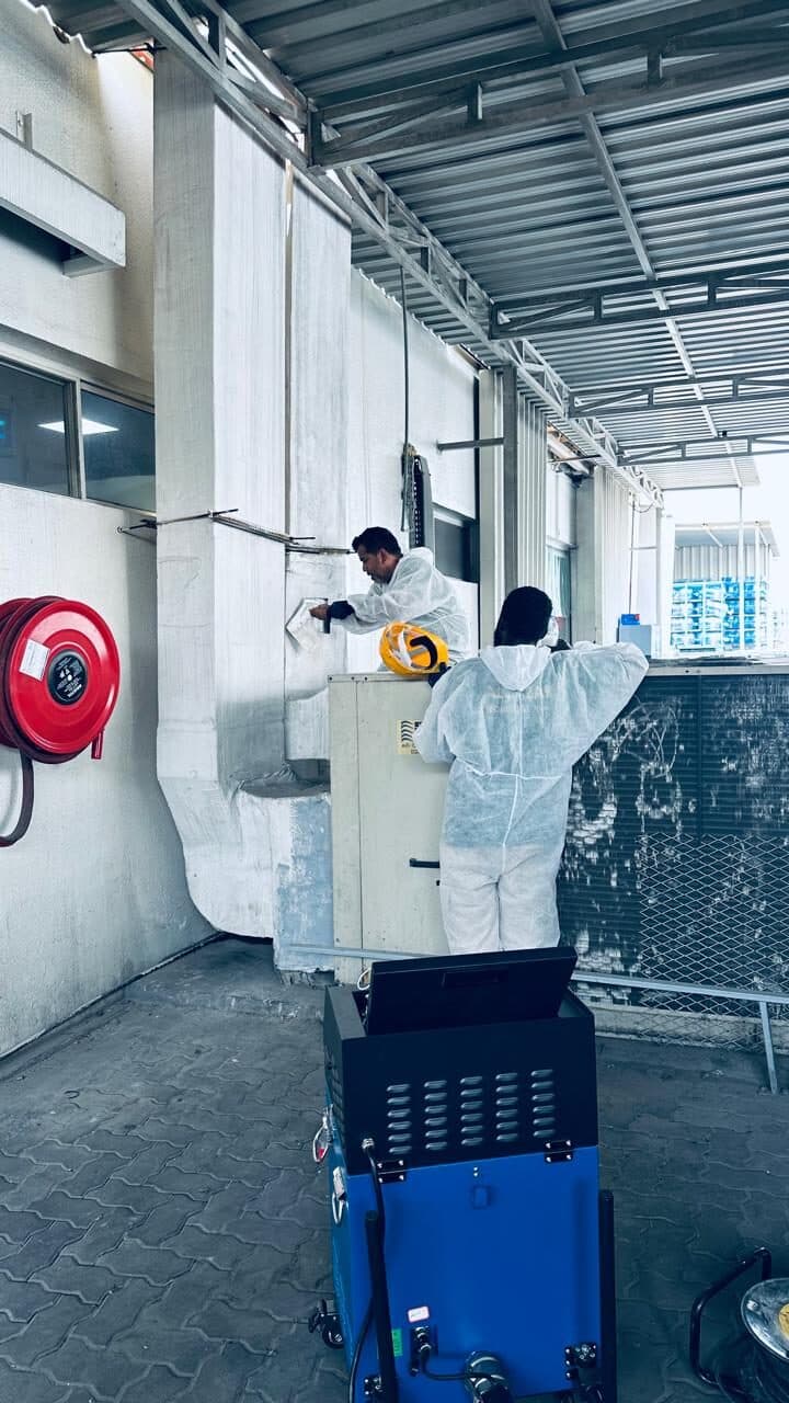 HoodEx technicians cleaning ventilation ductwork with a mechanical duct-cleaning machine at a commercial facility