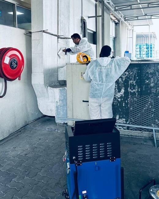 HoodEx technicians cleaning ventilation ductwork with a mechanical duct-cleaning machine at a commercial facility