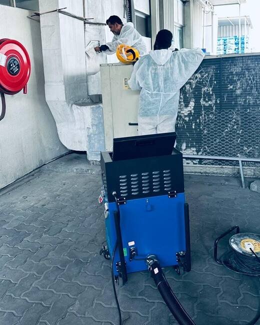 HoodEx technicians with duct-cleaning equipment working on ductwork at a commercial site